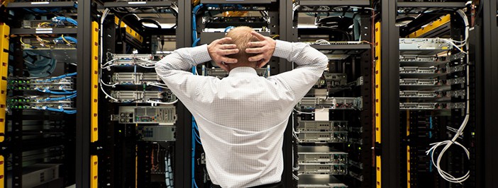 Man looking astonished in a network data center. Should have gotten disaster recovery.