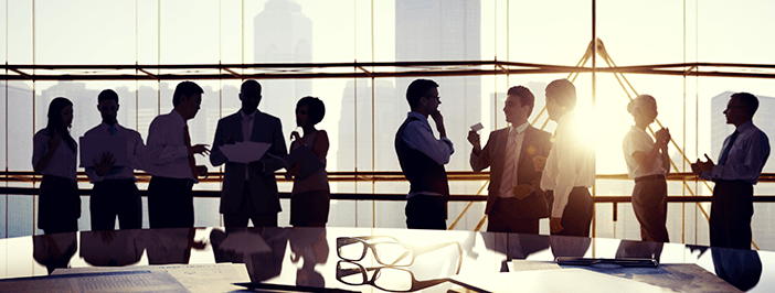 Group of Business People Discussing at Sunset Reflected Onto Table with Documents